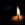 a lit candle is seen against a dark background