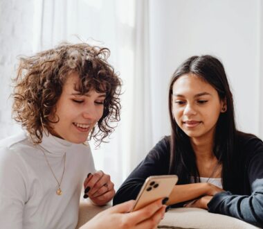 Women smiling using cellphone together.