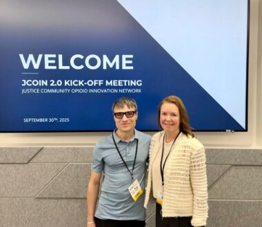 Sean Murphy and Kathryn McCollister pose for a portrait in front of a welcome screen.