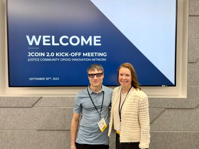 Sean Murphy and Kathryn McCollister pose for a portrait in front of a welcome screen.