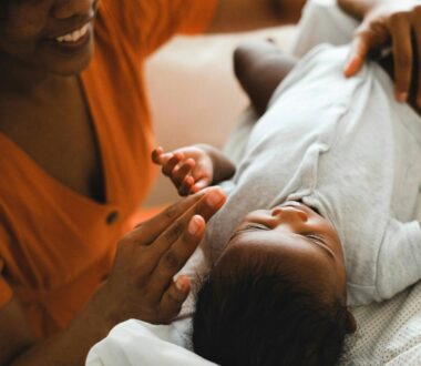 a black mother engages with her newborn baby on a couch indoors